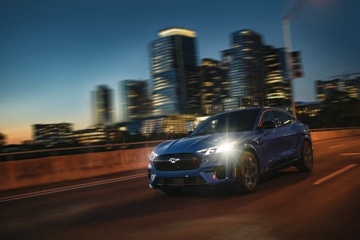 2024 Ford Mustang Mach-E® GT driving with a city in the background