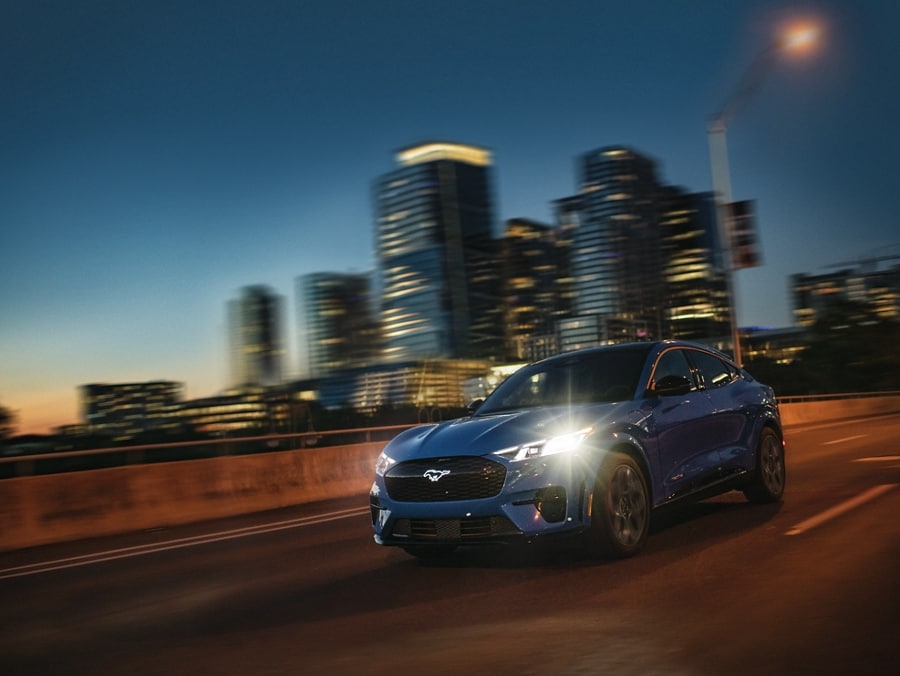 Front-end of a 2024 Ford Mustang Mach-E® Performance Edition against a blurry freeway in the background