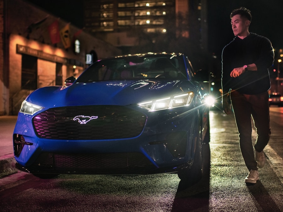 2024 Ford Mustang Mach-E® parked on the street at night with a man standing next to the vehicle