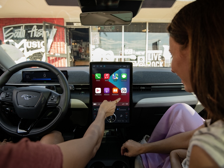 Two people inside the 2024 Ford Mustang Mach-E® using Apple CarPlay