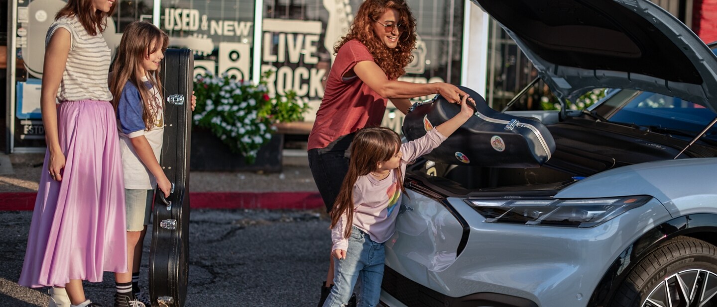 A woman and her daughter putting an instrument into the frunk of the 2024 Ford Mustang Mach-E®