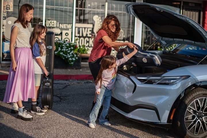 2024 Ford Mustang Mach-E® open Frunk® with people loading a cello in it