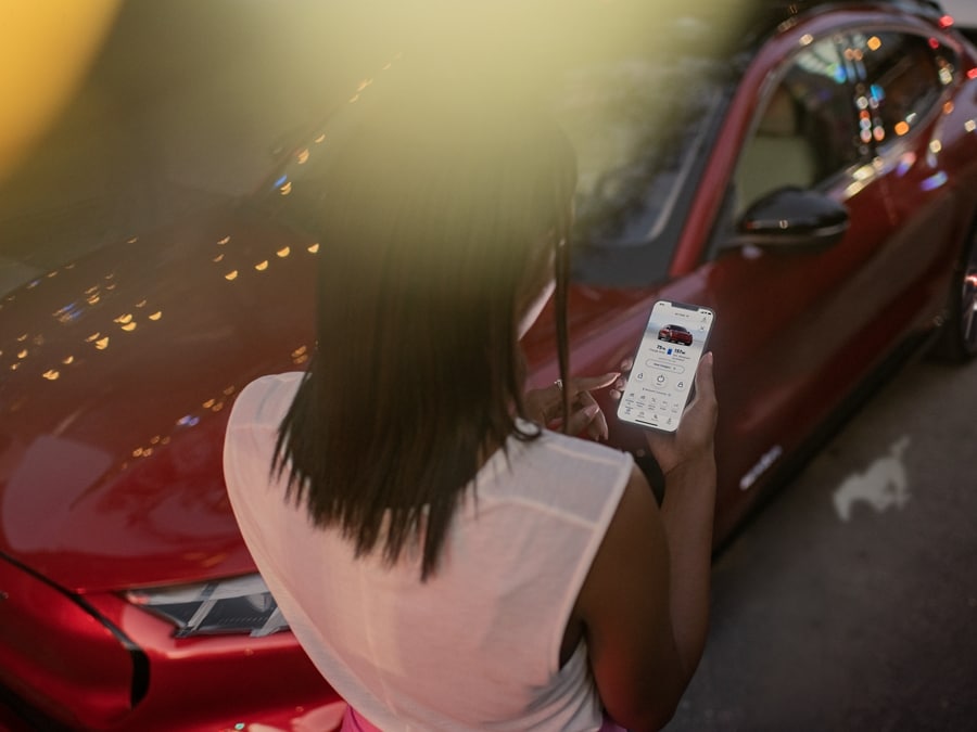 A person holding their smartphone and using the Ford Pass® app