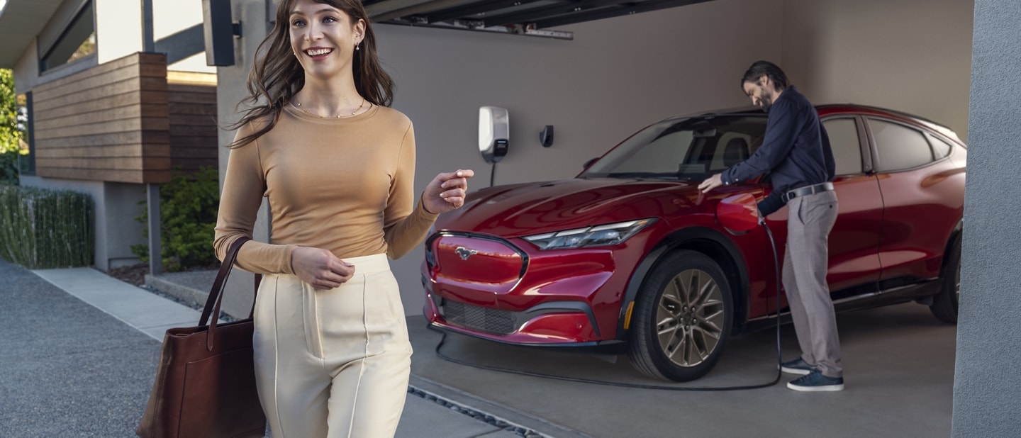 A man and woman standing nearby while the Ford Mustang Mach-E® is being charged in their home garage
