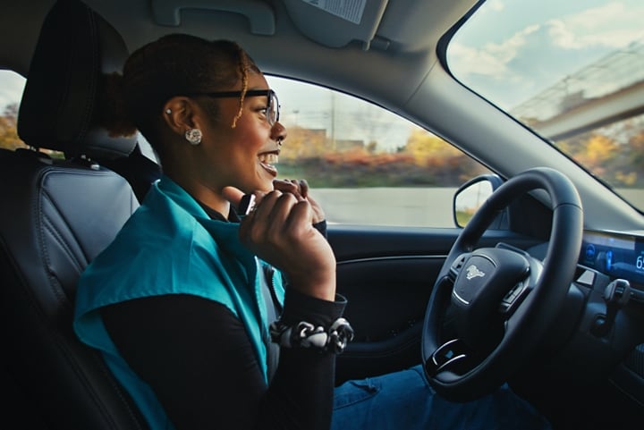 A woman in a 2024 Ford Mustang Mach-E® SUV sitting in the vehicle with her hands off the steering wheel