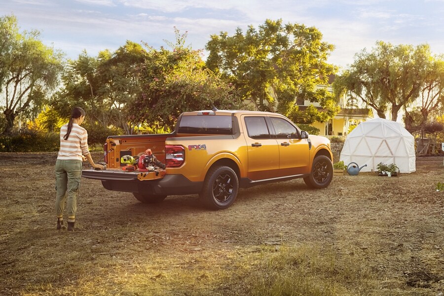 Woman in garden unloads plants from the Cyber Orange 2023 Ford Maverick® XLT truck multi-position tailgate