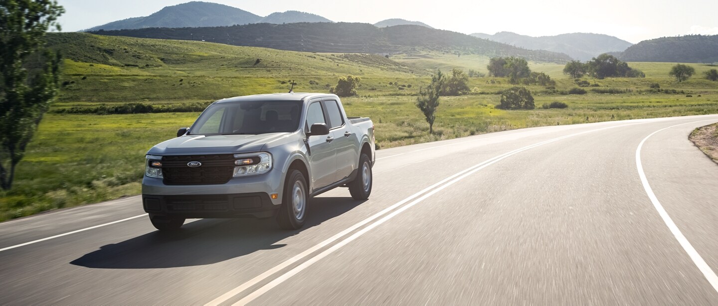 A 2023 Ford Maverick® truck on a country highway with hills in the background