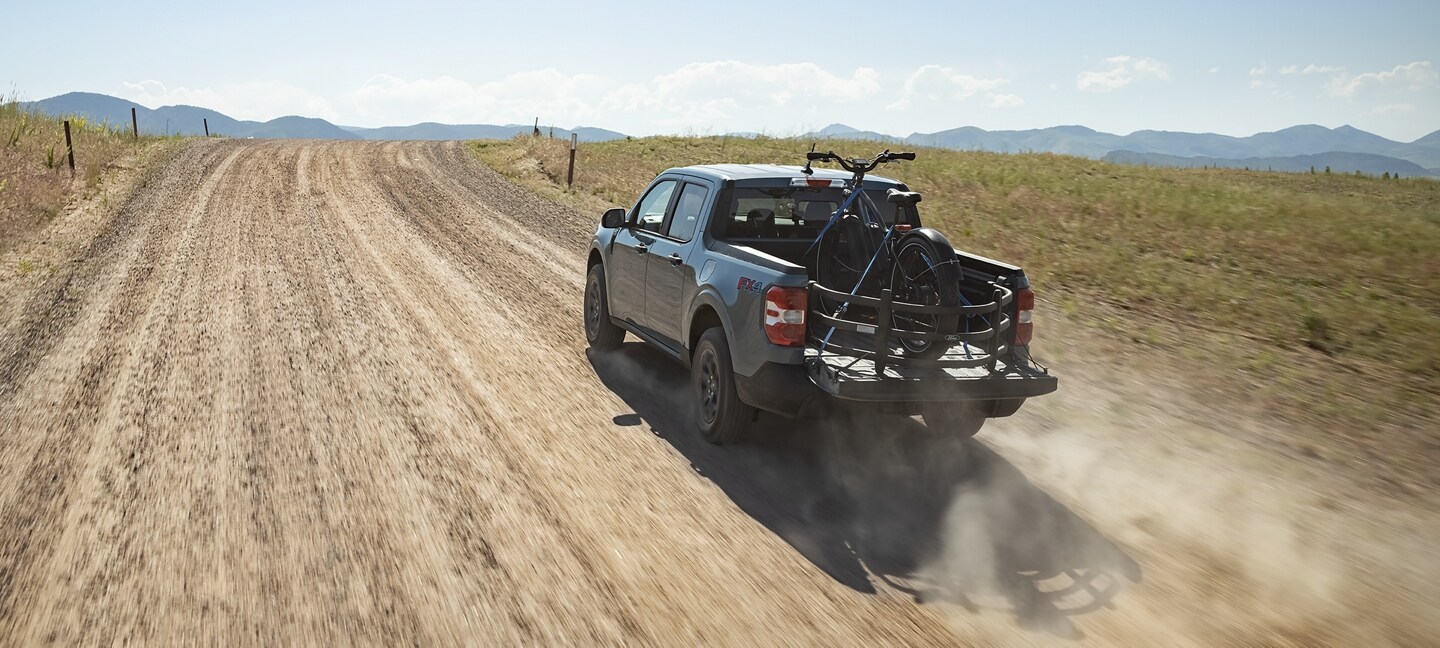 2023 Ford Maverick® truck with Bed Extender being driven on a dusty gravel road