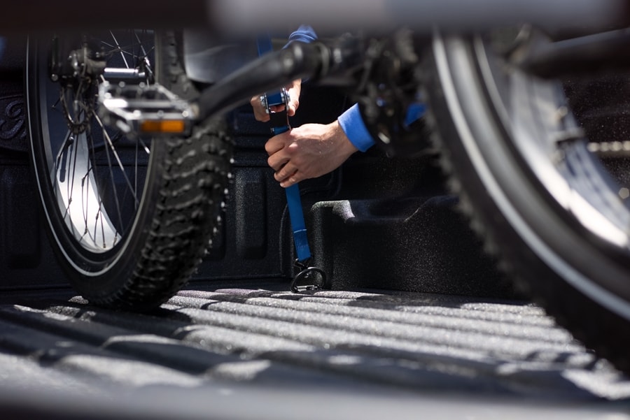 Man secures bike with a Tie-Down strap in the bed of a 2023 Ford Maverick® truck