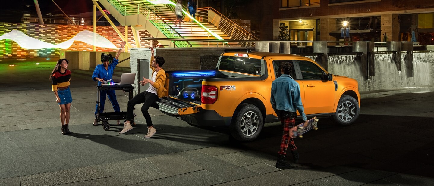 3 people and a DJ having a tailgate party with their Cyber Orange 2023 Ford Maverick® truck