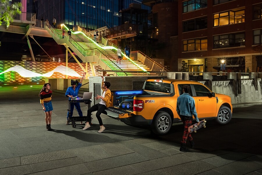 3 people and a DJ having a tailgate party with their Cyber Orange 2023 Ford Maverick® truck