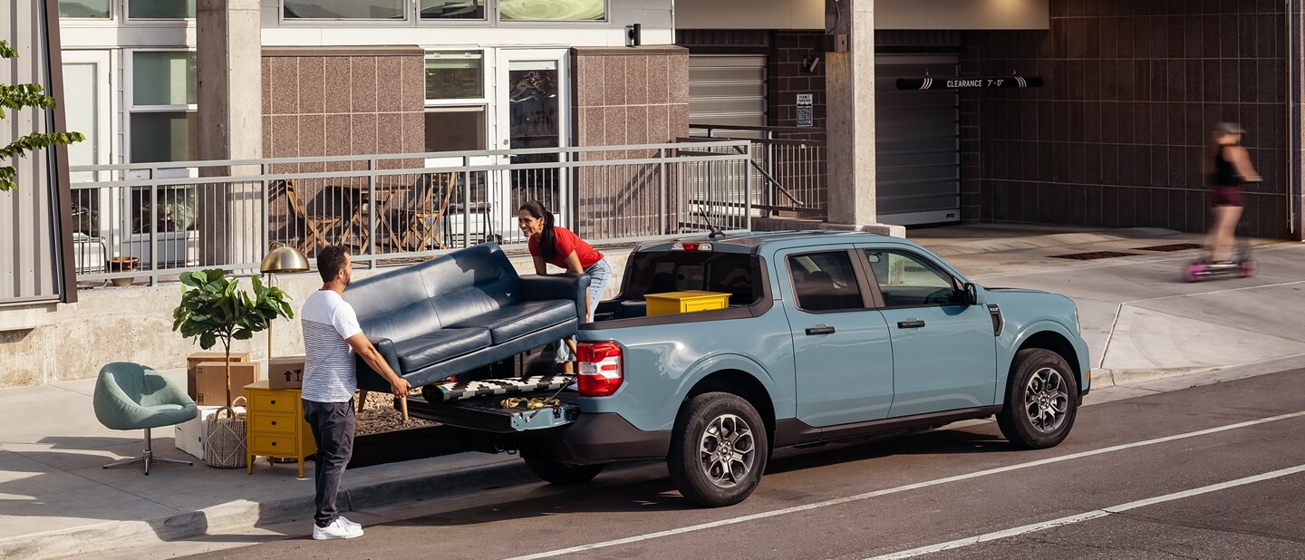 Two people unload a couch from the back of their 2023 Ford Maverick® truck in the colour Area 51