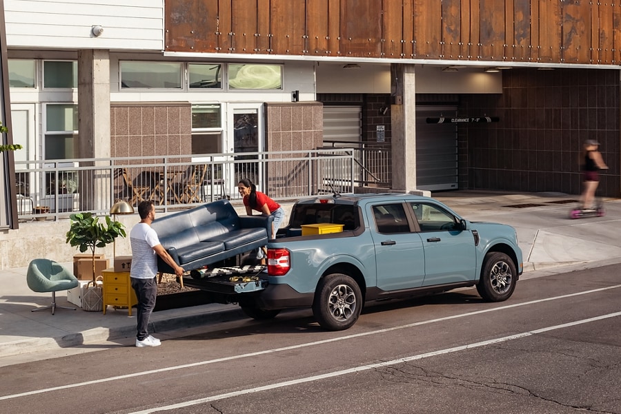 Two people loading a couch and household items into the bed of a 2023 Ford Maverick® truck