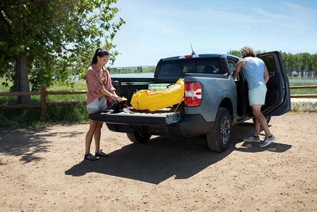 Couple unloads beach gear from a 2023 Ford Maverick® truck in the colour Area 51
