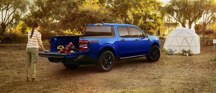 Close-up of a 2024 Ford Maverick® truck bed with a person's arms engaged with the 110V outlets and 12V electrical leads