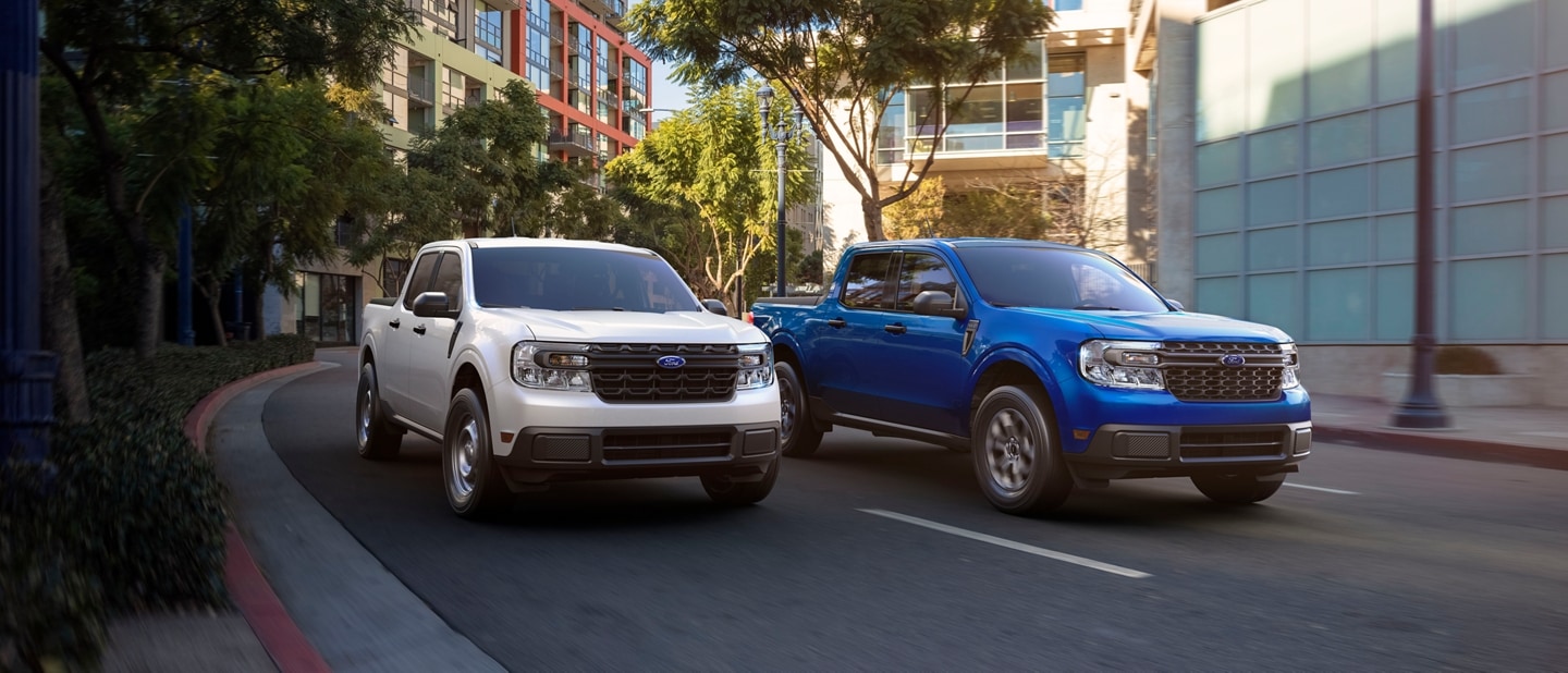Two 2024 Ford Maverick® trucks are being driven on a tree-lined city road