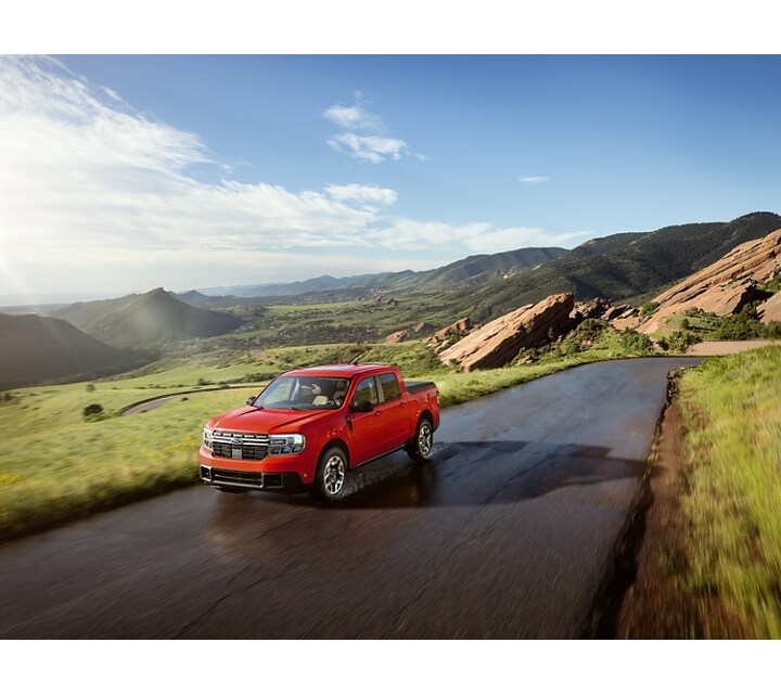 A 2024 Ford Maverick® truck is being driven on road in a scenic location with mountains in the background