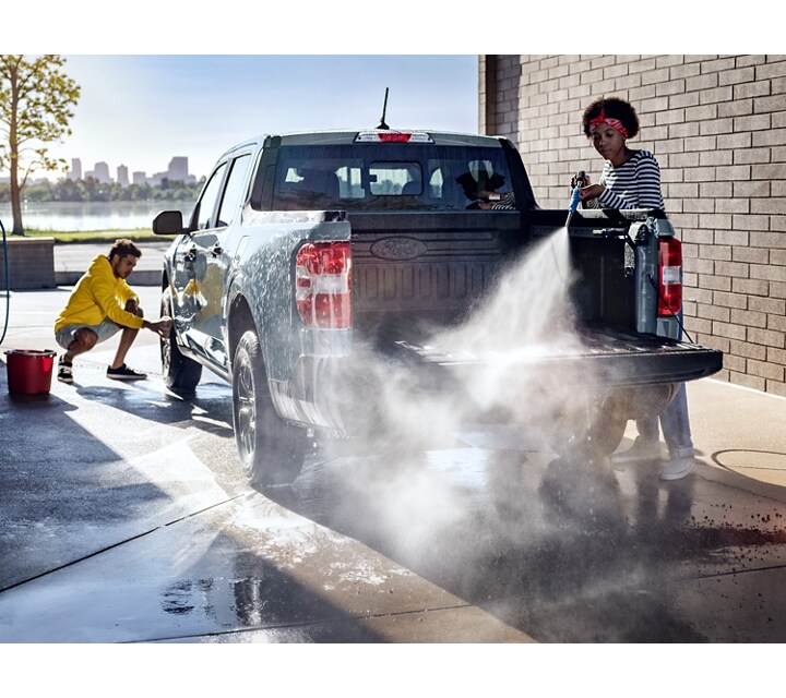 A 2024 Ford Maverick® truck is being sprayed with water by two people at an outdoor carwash