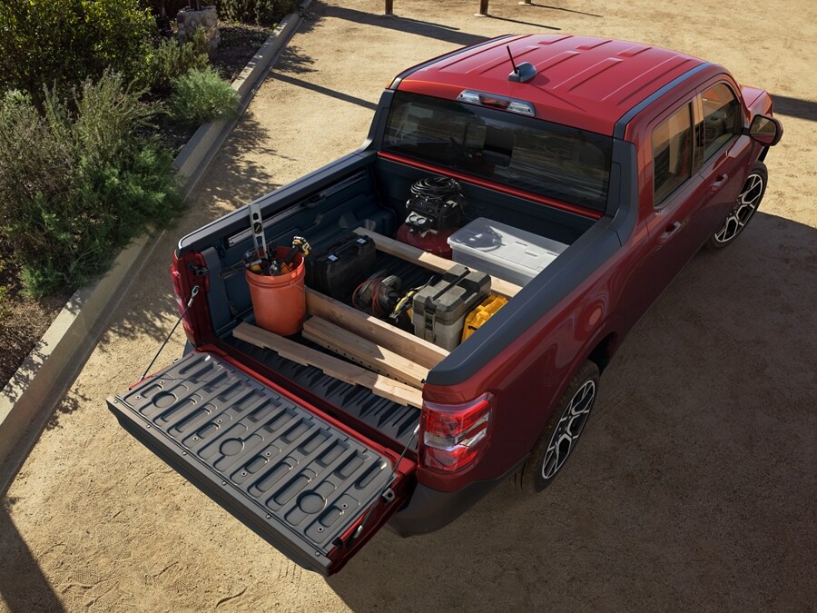 A red 2025 Ford Maverick® pickup with gardening items and lumber in the bed, with the tailgate lowered