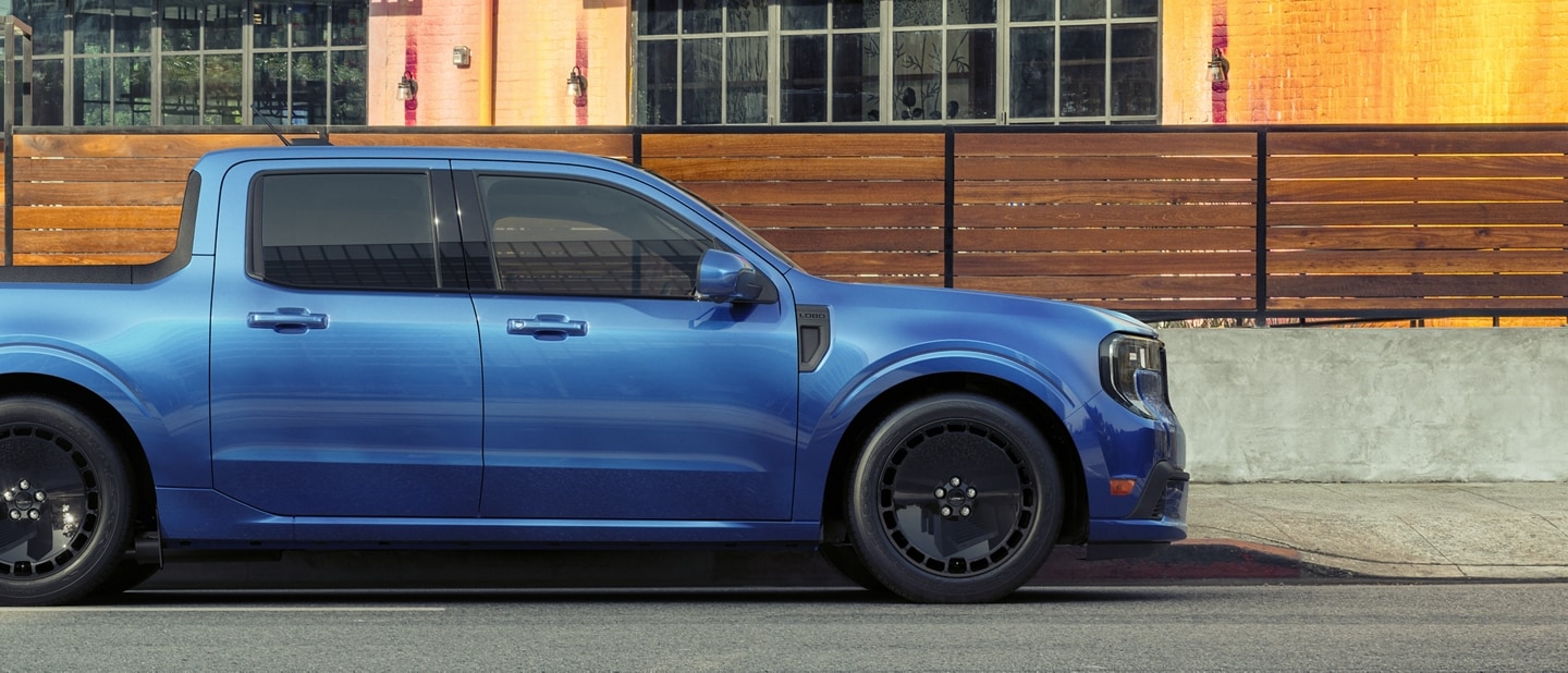 Profile view of a blue 2025 Ford Maverick® Lobo™ pickup parked in front of a restaurant patio