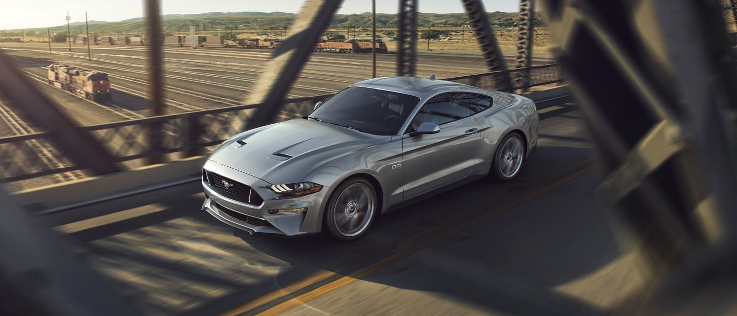 2023 Ford Mustang® coupe in Iconic Silver Metallic being driven across a bridge