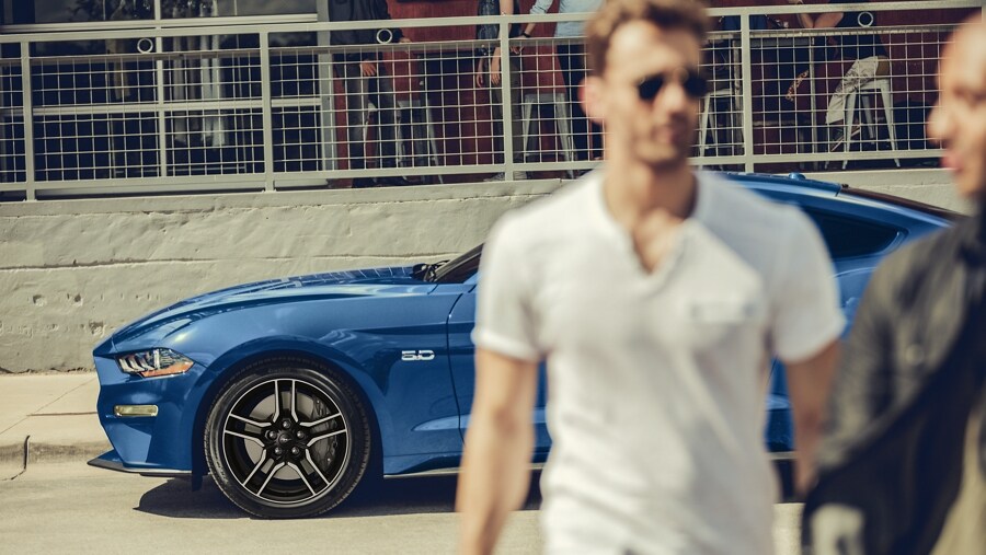 Two people walking away from a 2023 Ford Mustang® coupe with 18-inch by 8-inch wheels