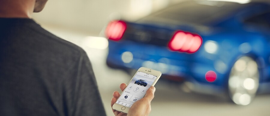 A person operates their phone to start a 2023 Ford Mustang® coupe