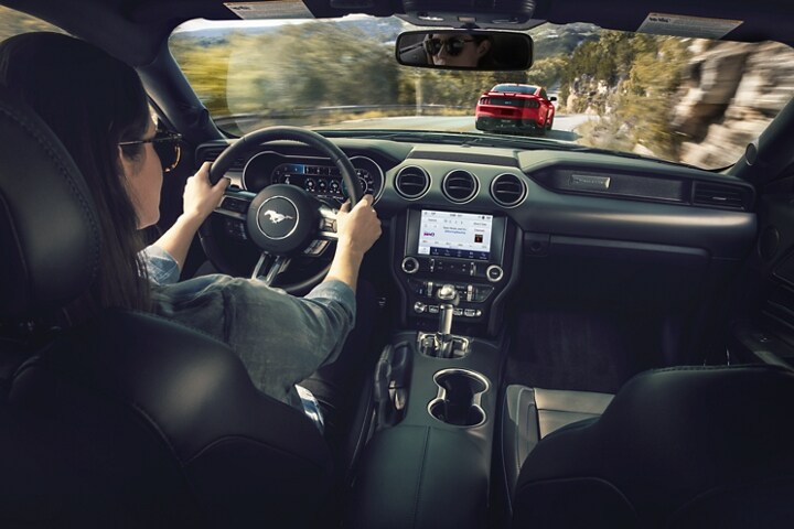 Person behind the wheel of a 2023 Ford Mustang® coupe driving on a mountainous road