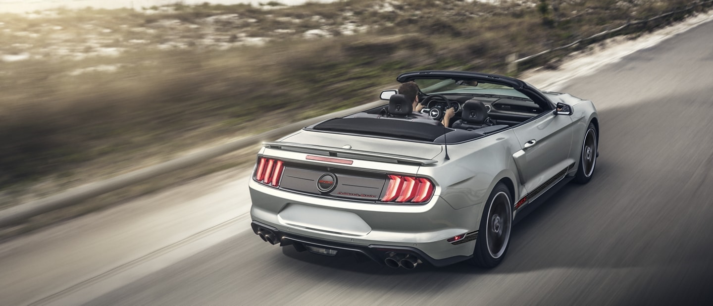 Rear view of a 2023 Ford Mustang® convertible being driven down an oceanside highway