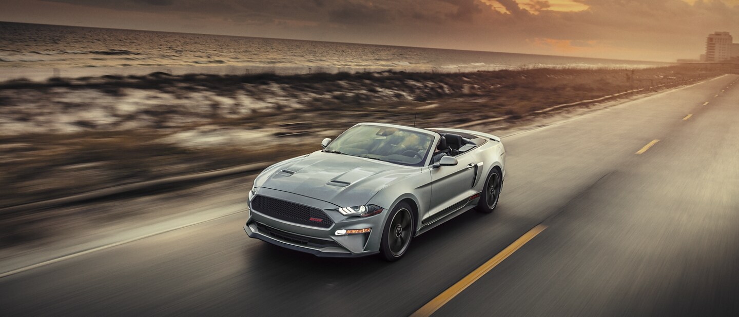 2023 Ford Mustang® convertible with California Special Package with the top down being driven on an oceanside highway