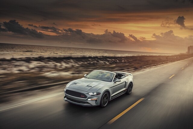 2023 Ford Mustang® convertible with California Special Package with the top down being driven on an oceanside highway