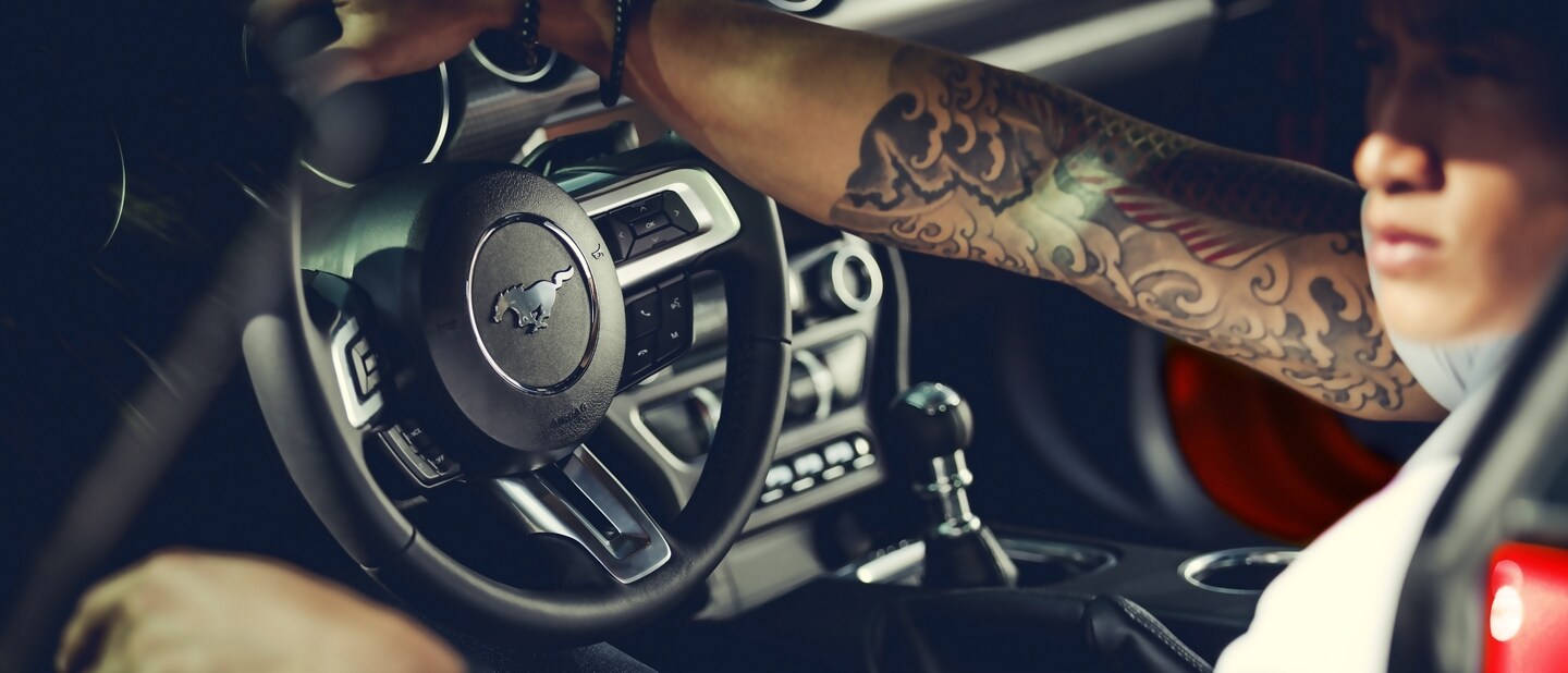 A person in the driver’s seat of a 2023 Ford Mustang® coupe