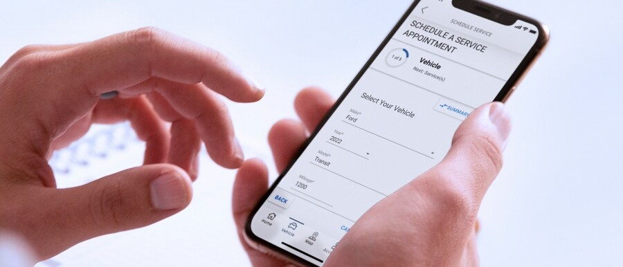 A hand holds a smartphone displaying the FordPass® App