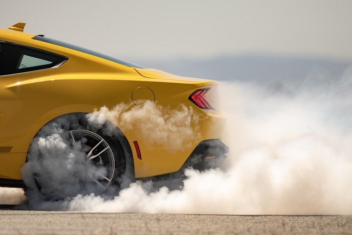 2024 Ford Mustang® EcoBoost® coupe in Yellow Splash Metallic Tri-coat (extra-cost paint) with driver doing burnouts