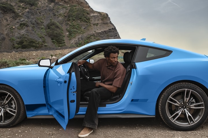 Person exiting a 2024 Ford Mustang® EcoBoost® model in Grabber Blue Metallic