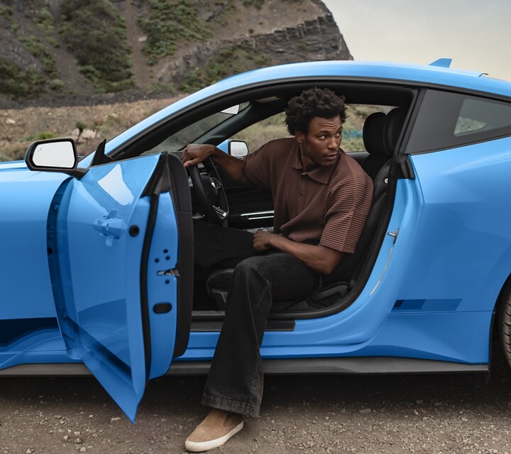 Person exiting a 2024 Ford Mustang® coupe parked in the desert