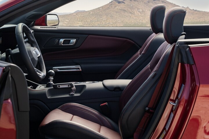 Parked 2024 Ford Mustang® convertible with the driver's side door open showing the available Carmine Red interior