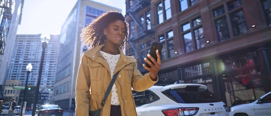 Person walking down a city street using a smartphone