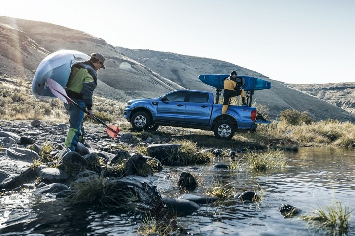 2023 Ford Ranger® in Velocity Blue with kayakers at stream with an available Ford bedmounted rack accessory