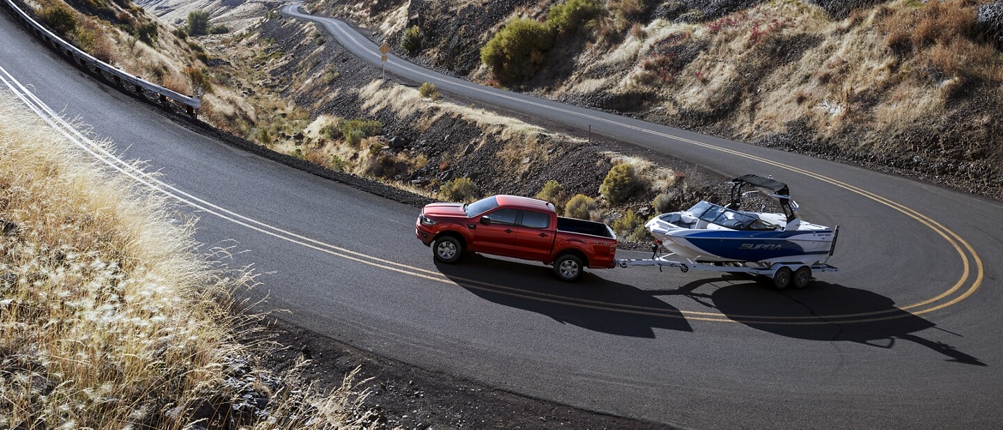 2023 Ford Ranger® FX4 shown in Hot Pepper Metallic towing a boat up a winding