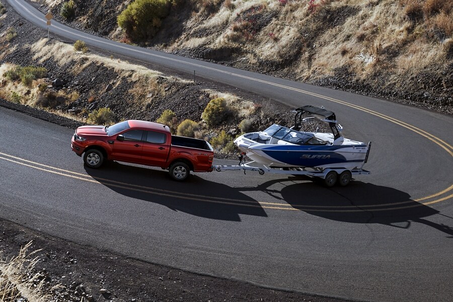2023 Ford Ranger® in Hot Pepper Red Metallic Tinted Clearcoat towing boat up winding road