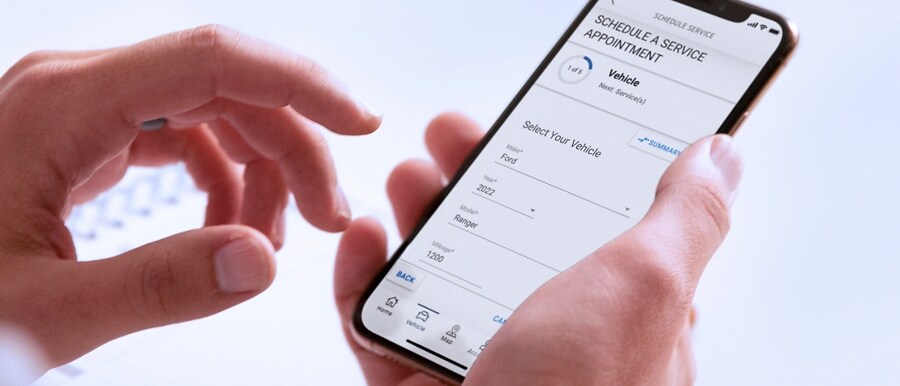 A hand holding a smartphone with the FordPass® App open
