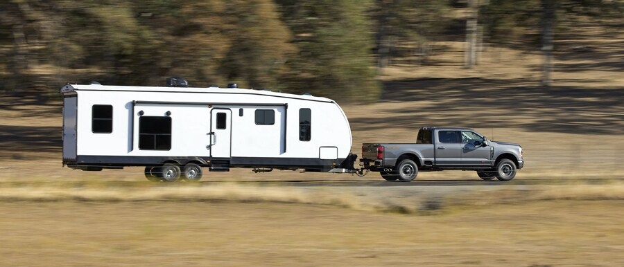 2023 Ford Super Duty® F-250 Tremor Off-Road Package pulling a camper on a dirt road