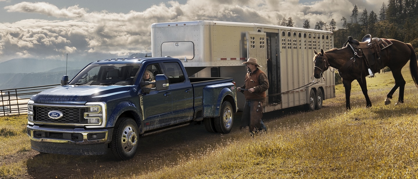 A man walking toward a 2023 Ford Super Duty® F-450 King Ranch® DRW hitched to a horse trailer