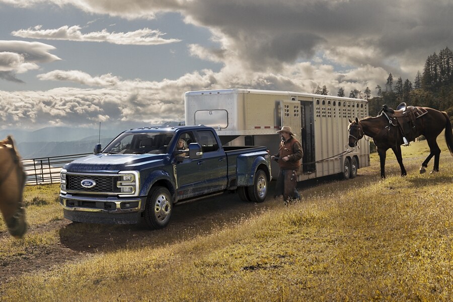 A man walking toward a 2023 Ford Super Duty® F-450 King Ranch® DRW hitched to a horse trailer