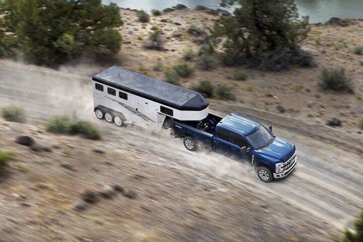 2023 Ford Super Duty® truck with a trailer being driven down a rocky road