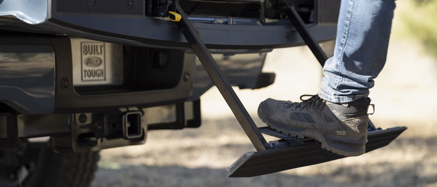 Close-up of a person stepping on the rear tailgate step on a 2023 Ford Super Duty® pickup