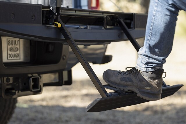 Close-up of a person stepping on the rear tailgate step on a 2023 Ford Super Duty® pickup