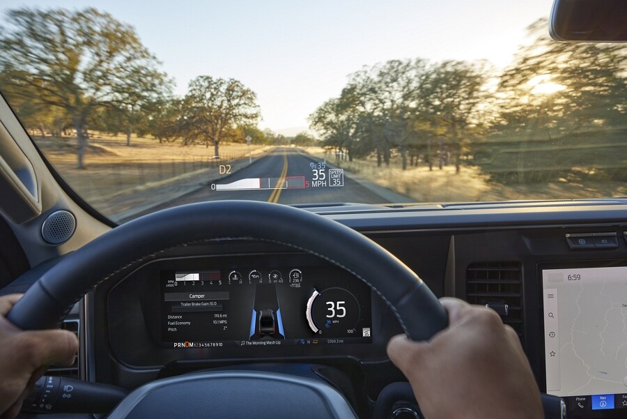 A person holding the steering wheel with the head-up display projected onto the windshield