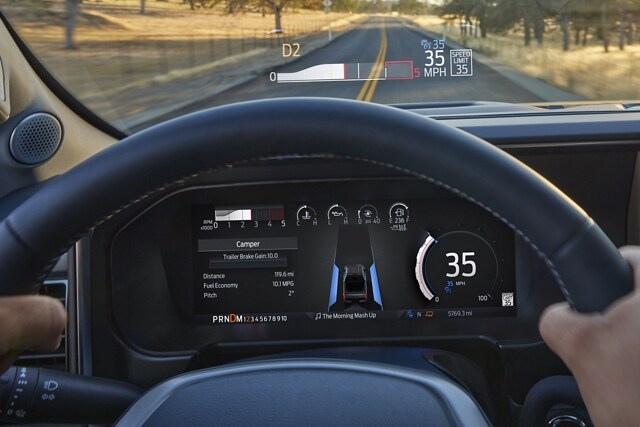 A person holding the steering wheel with the head-up display projected onto the windshield